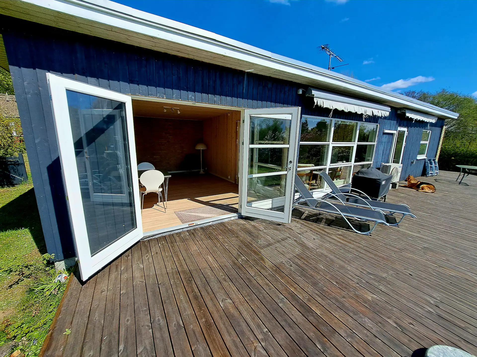 Sommerhuset set udefra med have og blå himmel